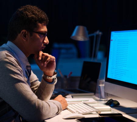Young man working on computer at night in dark office