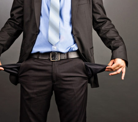 Business man showing his empty pockets  on gray background