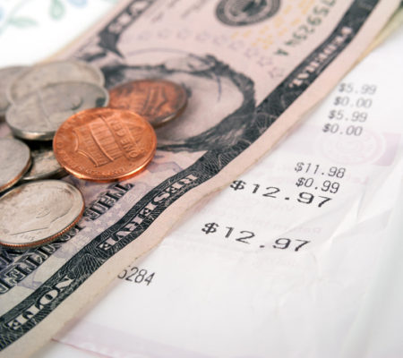 Restaurant bill with dollar bills (tips) on a plate and receipt close up