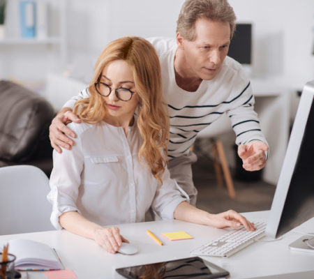 Feeling no subordination. Confident positive playful boss standing in the office while working and hugging the secretary