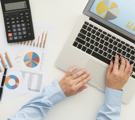 Financial analyst using laptop computer analyzing business data on desk. top view. Accounting concept.