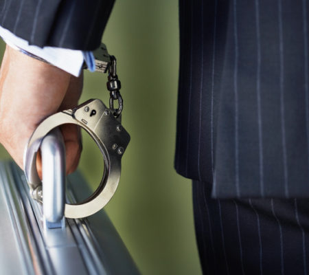 Closeup midsection of a businessman handcuffed to briefcase against green background